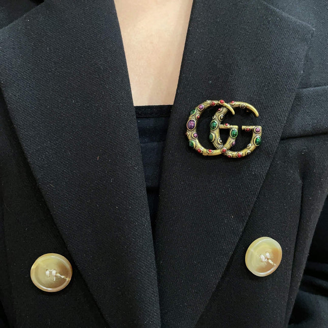GUCCI 26S INTERLOCKING G MULTICOLOR GEM LOGO BROOCH IN ANTIQUE GOLD TONE METAL 625634