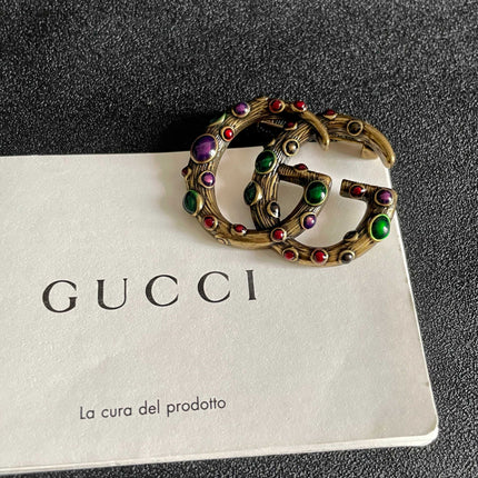 GUCCI 26S INTERLOCKING G MULTICOLOR GEM LOGO BROOCH IN ANTIQUE GOLD TONE METAL 625634
